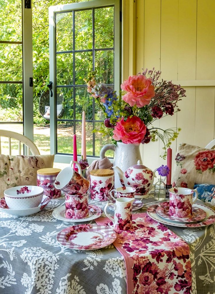 A table by the window  in a summerhouse dressed with our pink floral and gingham Josie's Blush tableware collection